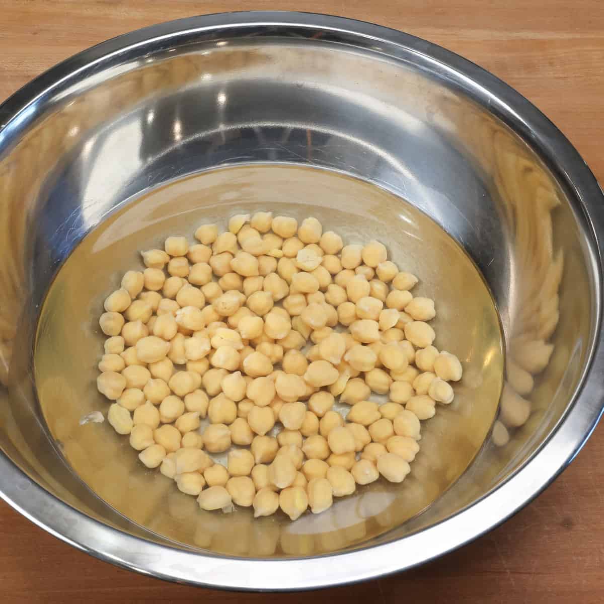 a bowl of dried chickpeas soaking in water.