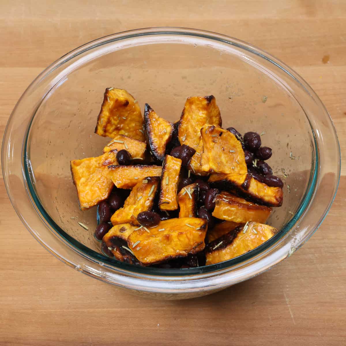 roasted sweet potatoes and black beans tossed in a vinaigrette in a mixing bowl.