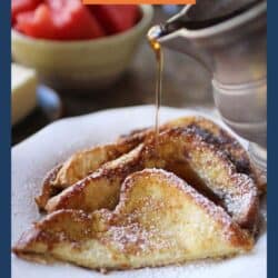 four halves of french toast on a white plate with powder sugar on top and syrup being poured on it.