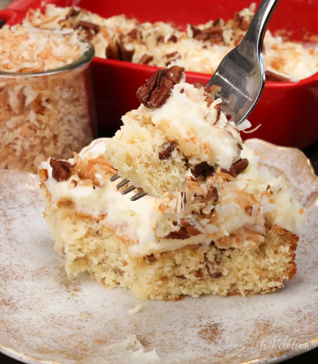 a fork on the side of a plate with a slice of Italian Cream Cake on it.