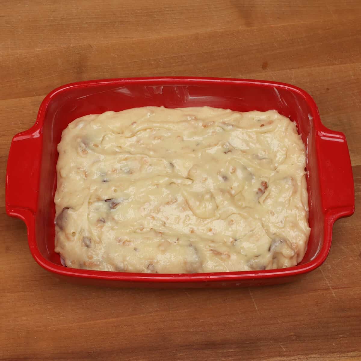 italian cream cake batter in a small red baking dish.
