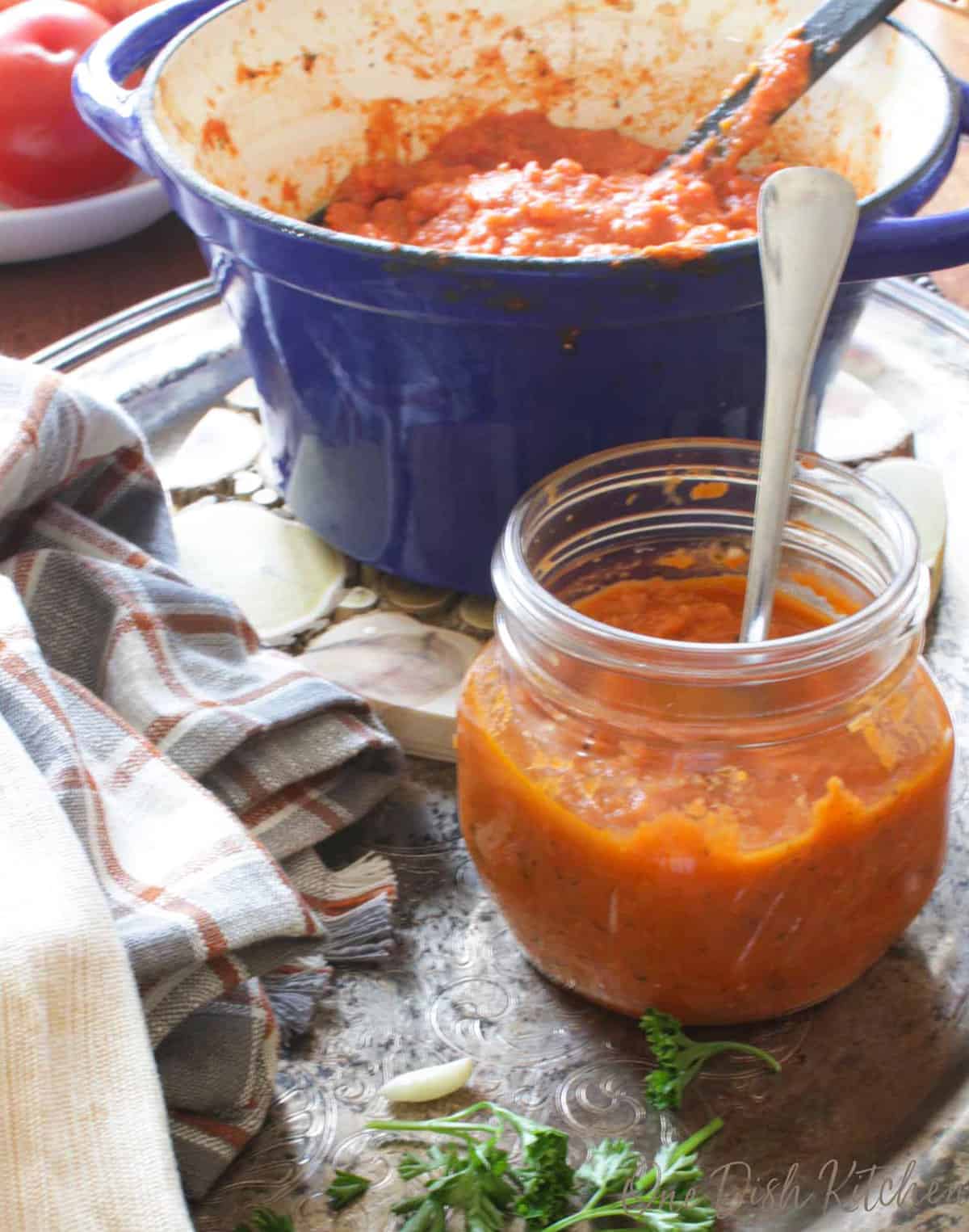 tomato sauce in a small ball mason jar with a spoon in it.
