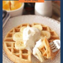 One waffle on a glass plate with bananas and cream on top.