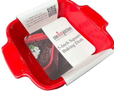 Red 5-inch square baking dish with One Dish Kitchen branded paper sleeve around it.