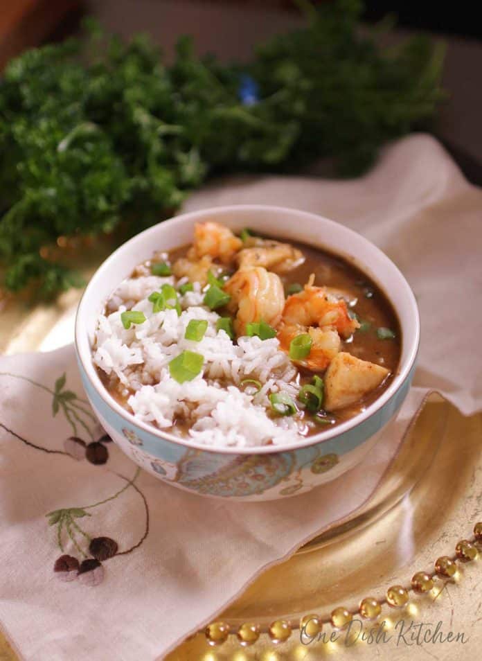 a bowl of gumbo with rice on a white napkin.