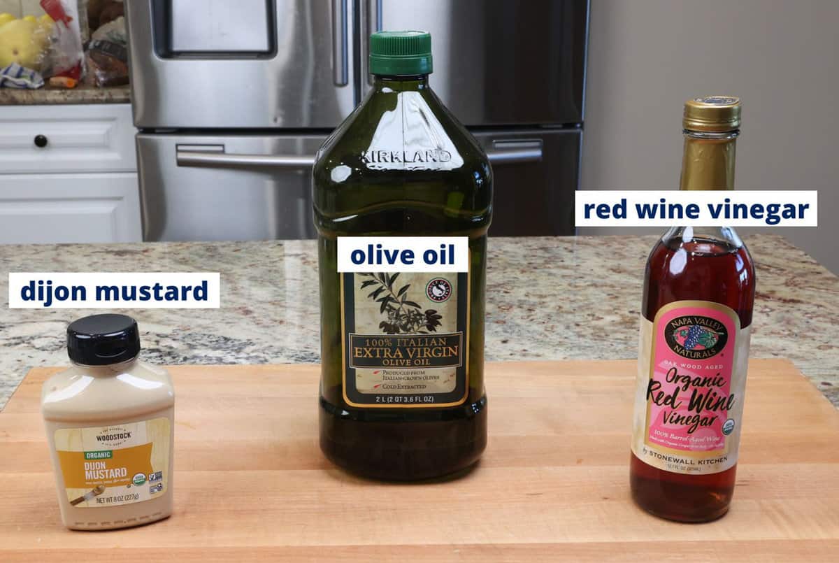 dijon mustard, red wine vinegar, and olive oil on a kitchen counter.