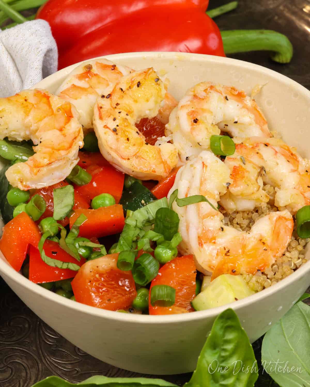 a quinoa bowl topped with cooked shrimp and fresh vegetables.