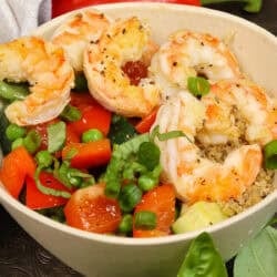 a quinoa bowl with shrimp and vegetables on a silver tray.