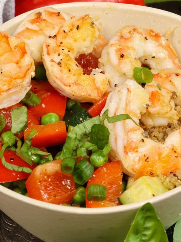 a quinoa bowl with shrimp and vegetables on a silver tray.