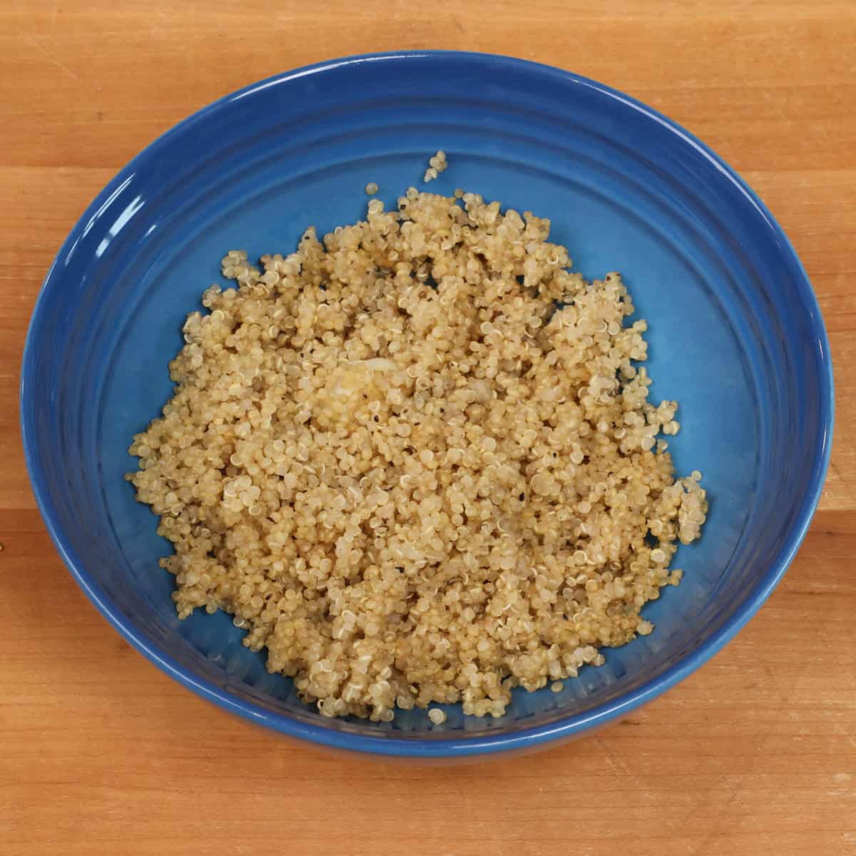 a blue bowl filled with cooked quinoa.
