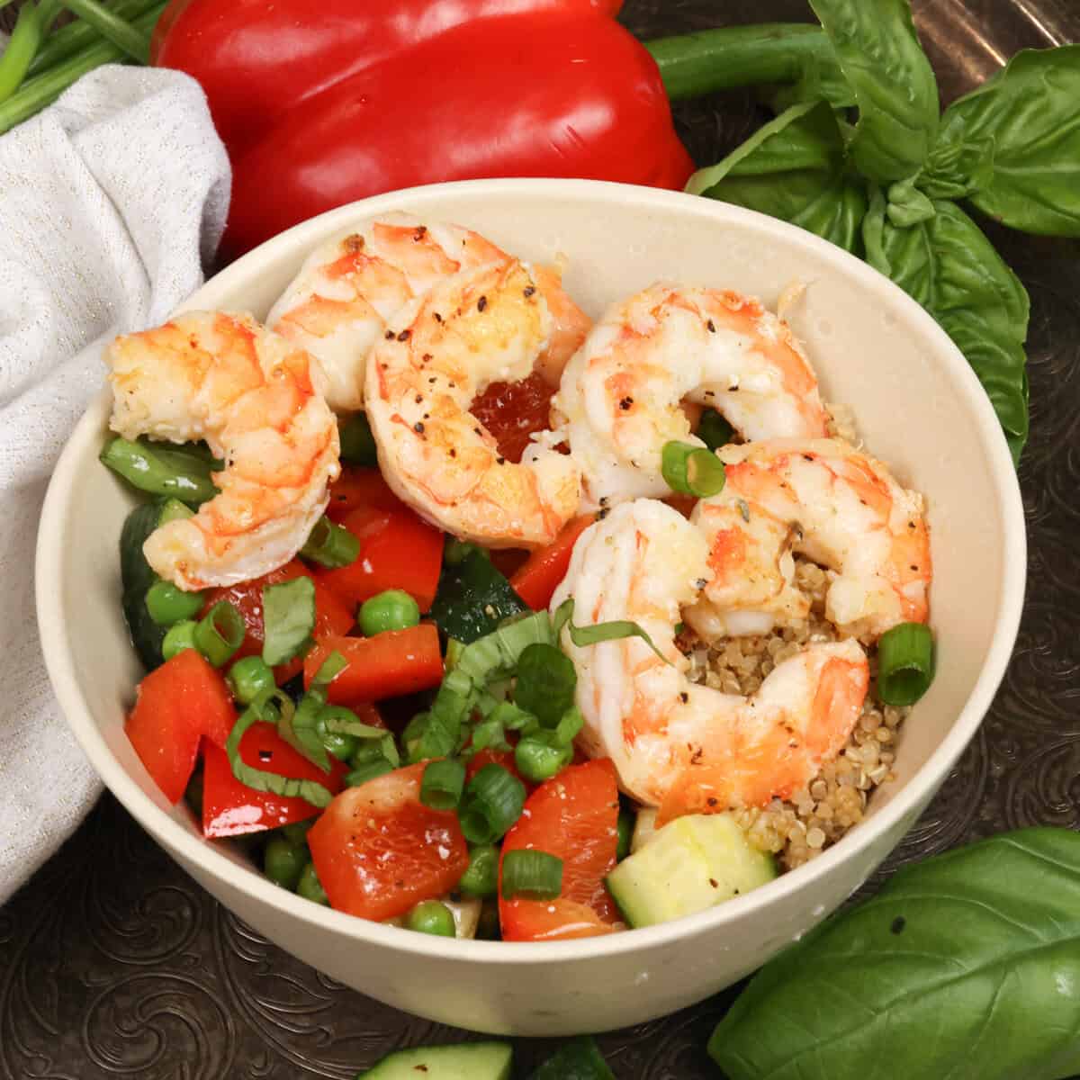 a quinoa bowl with shrimp and vegetables on a silver tray.
