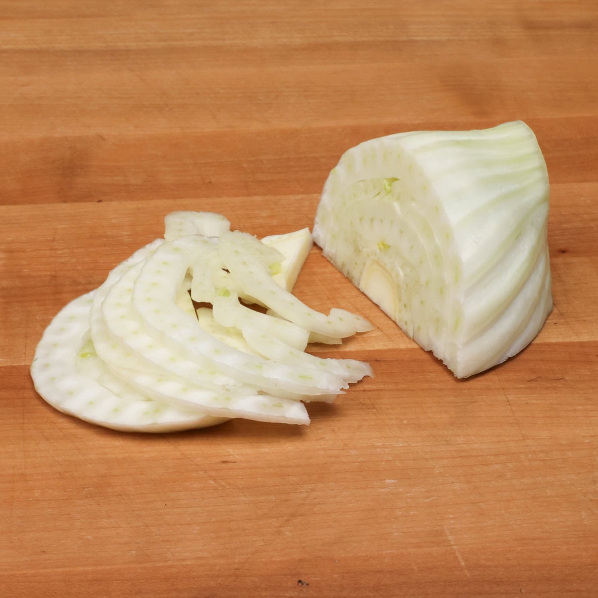 Showing how to thinly slice fennel for salad using a sharp chef's knife for a mild anise flavor.