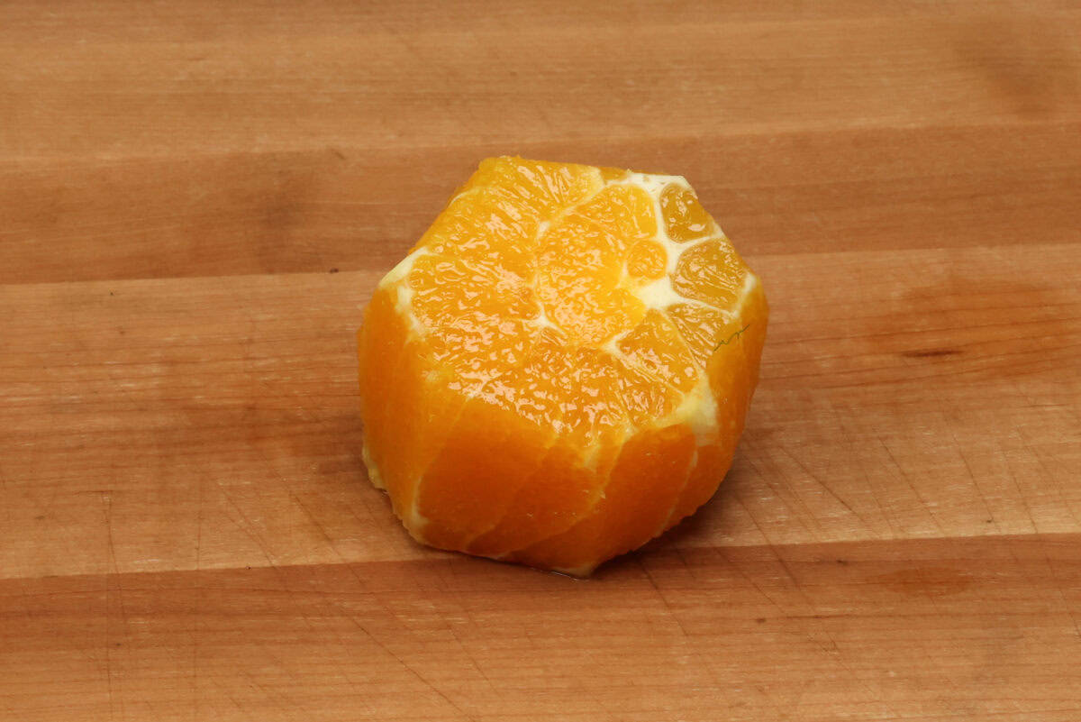 an orange without the peel on a cutting board.