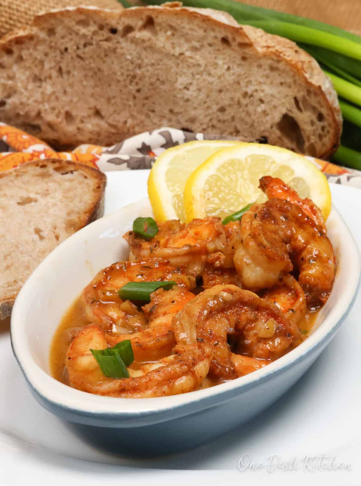 a bowl of barbecue shrimp topped with sliced green onions.