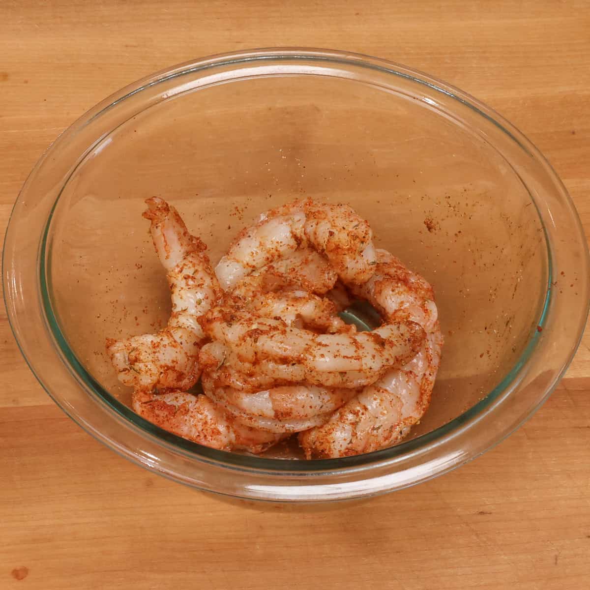 raw shrimp tossed in creole seasoning in a small bowl.