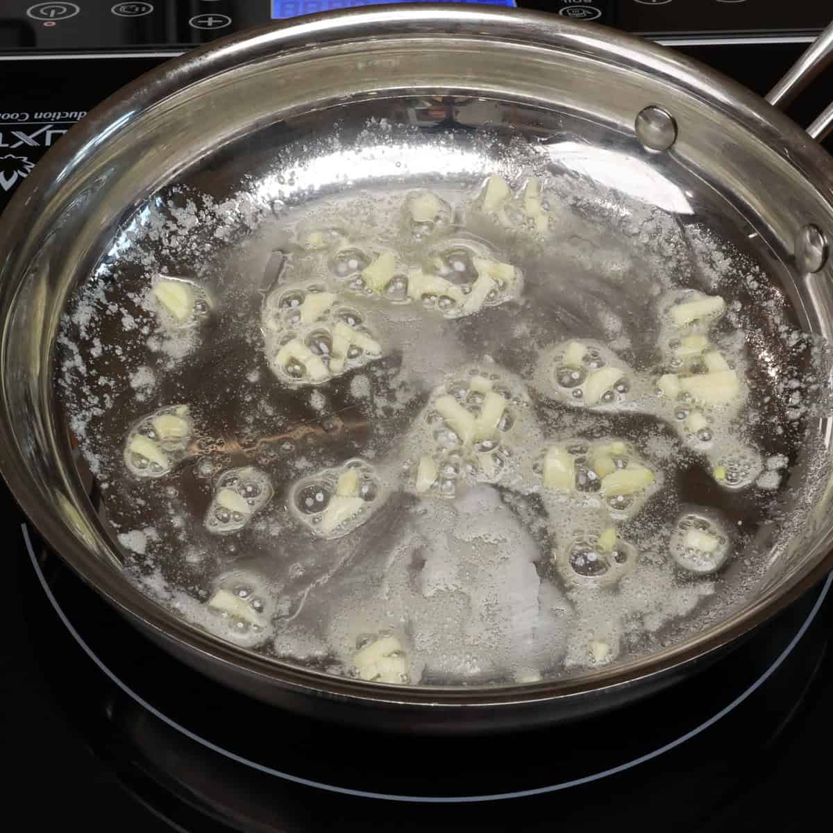 chopped garlic simmering in a pan with butter.