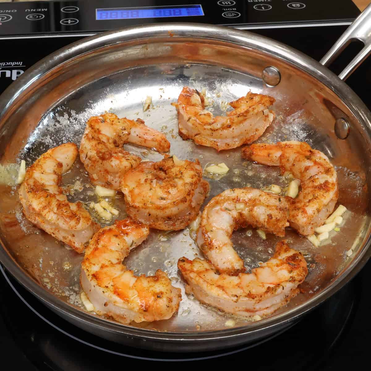 seven shrimp cooking in a skillet.