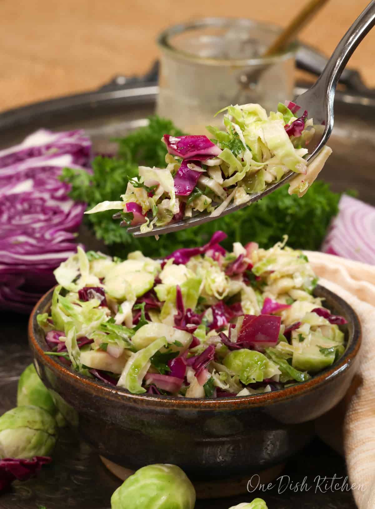 a shaved brussels sprouts salad in a bowl with a fork on the side.