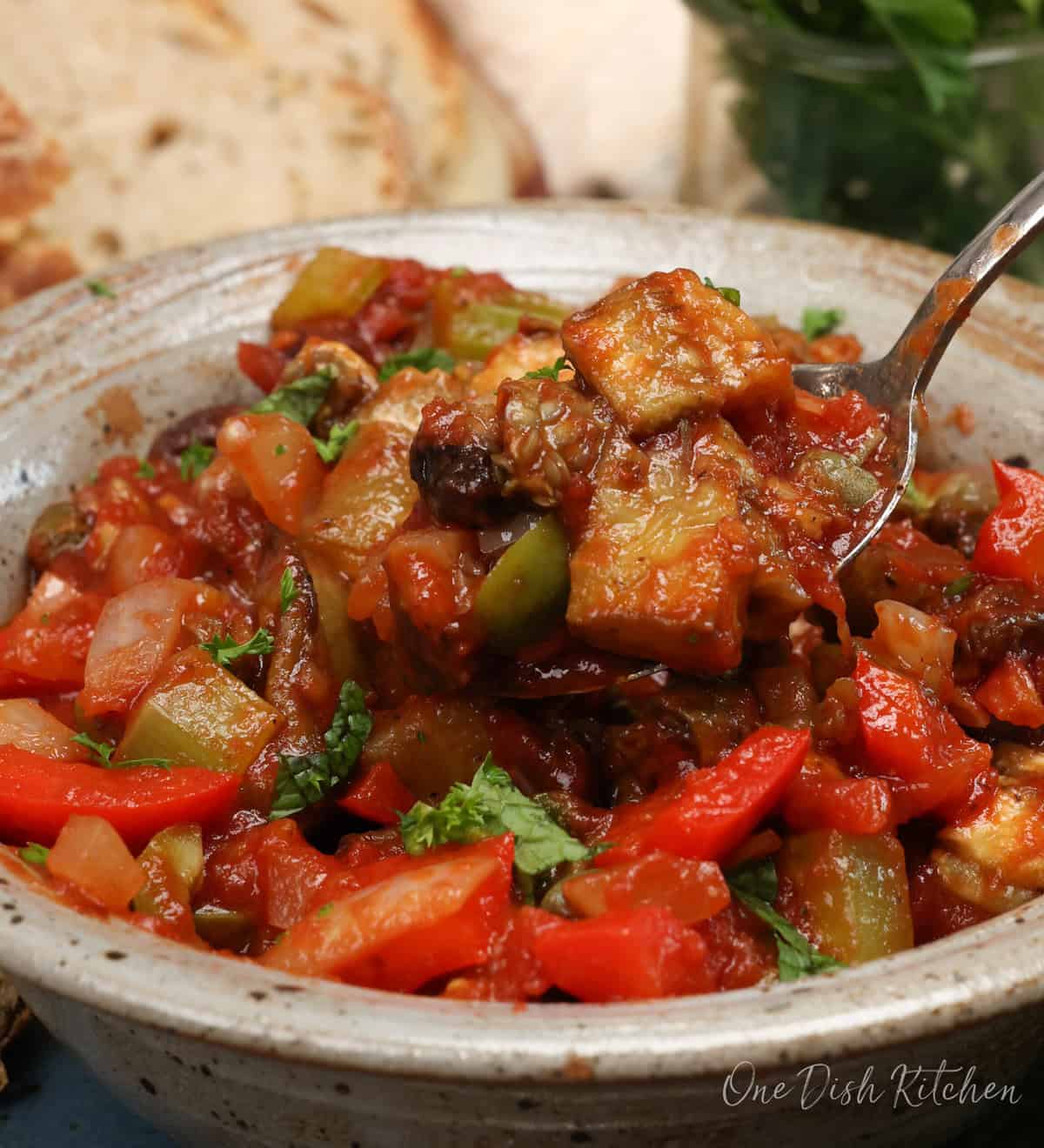 a bowl of caponata with a spoon on the side of the bowl.