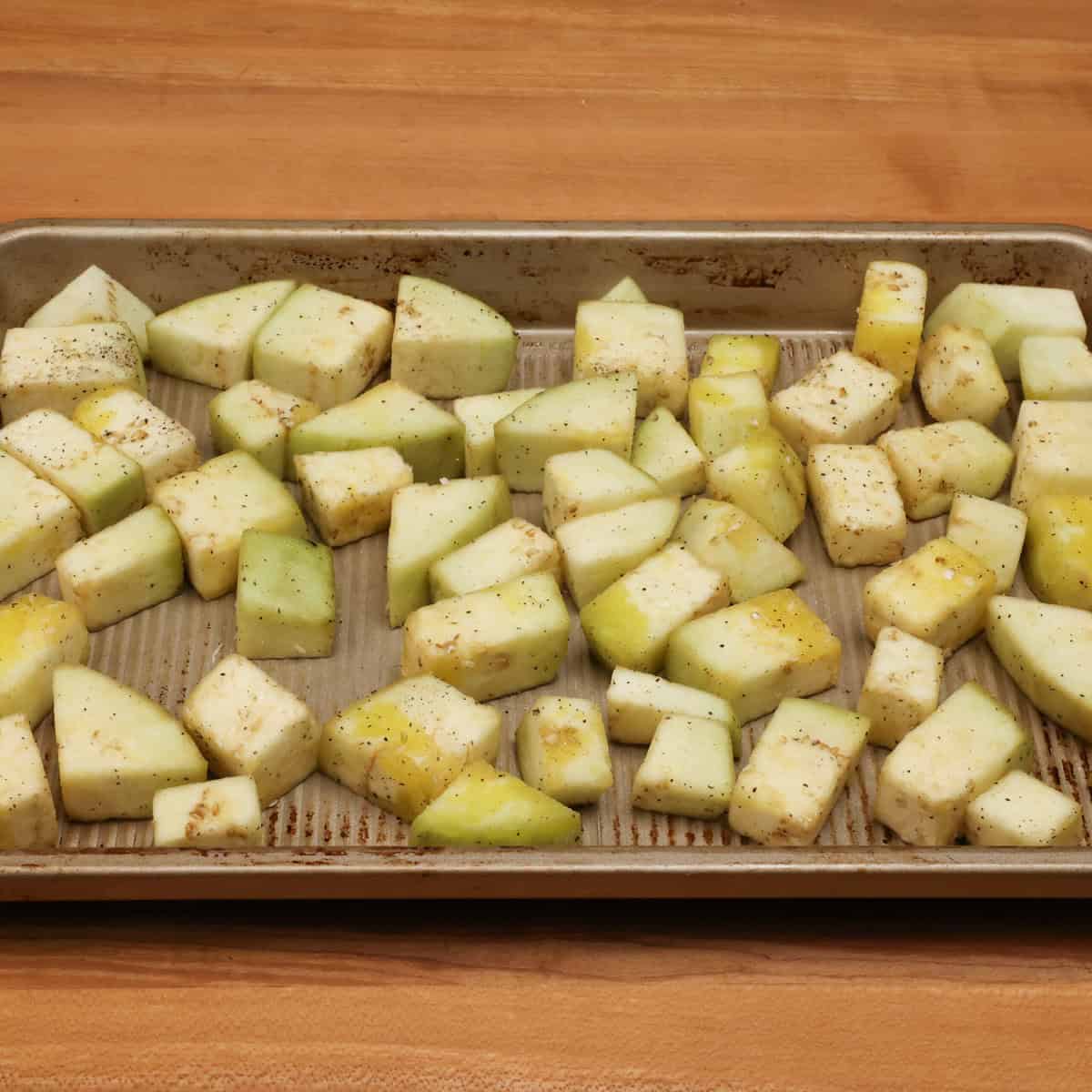 peeled and cubed eggplant on a rimmed baking sheet.