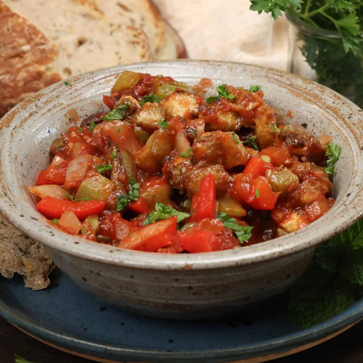 caponata in a blue bowl topped with fresh parsley.