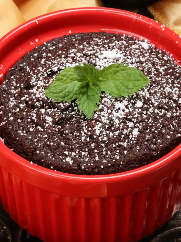 a mini chocolate cake topped with powdered sugar and fresh mint.