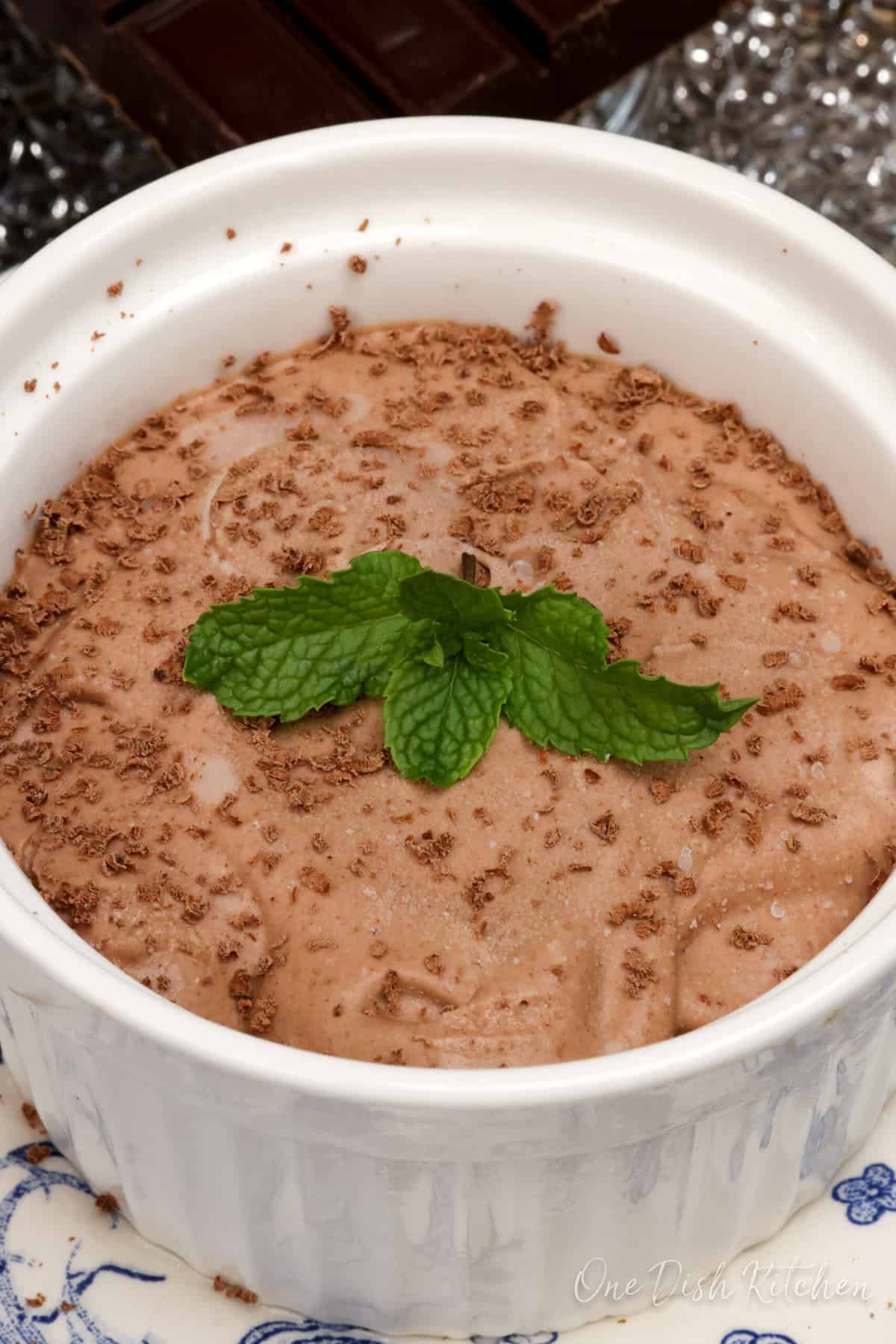 a white ramekin filled with homemade chocolate ice cream topped with a sprig of fresh mint.