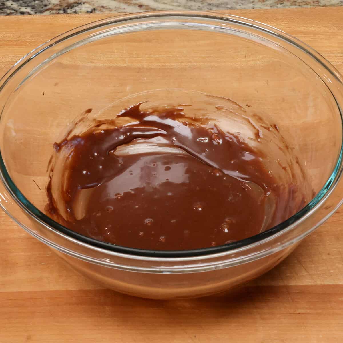 melted chocolate, vanilla, sweetened condensed milk and cocoa powder in a bowl.