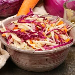 a small bowl of vinegar based coleslaw on a silver tray.