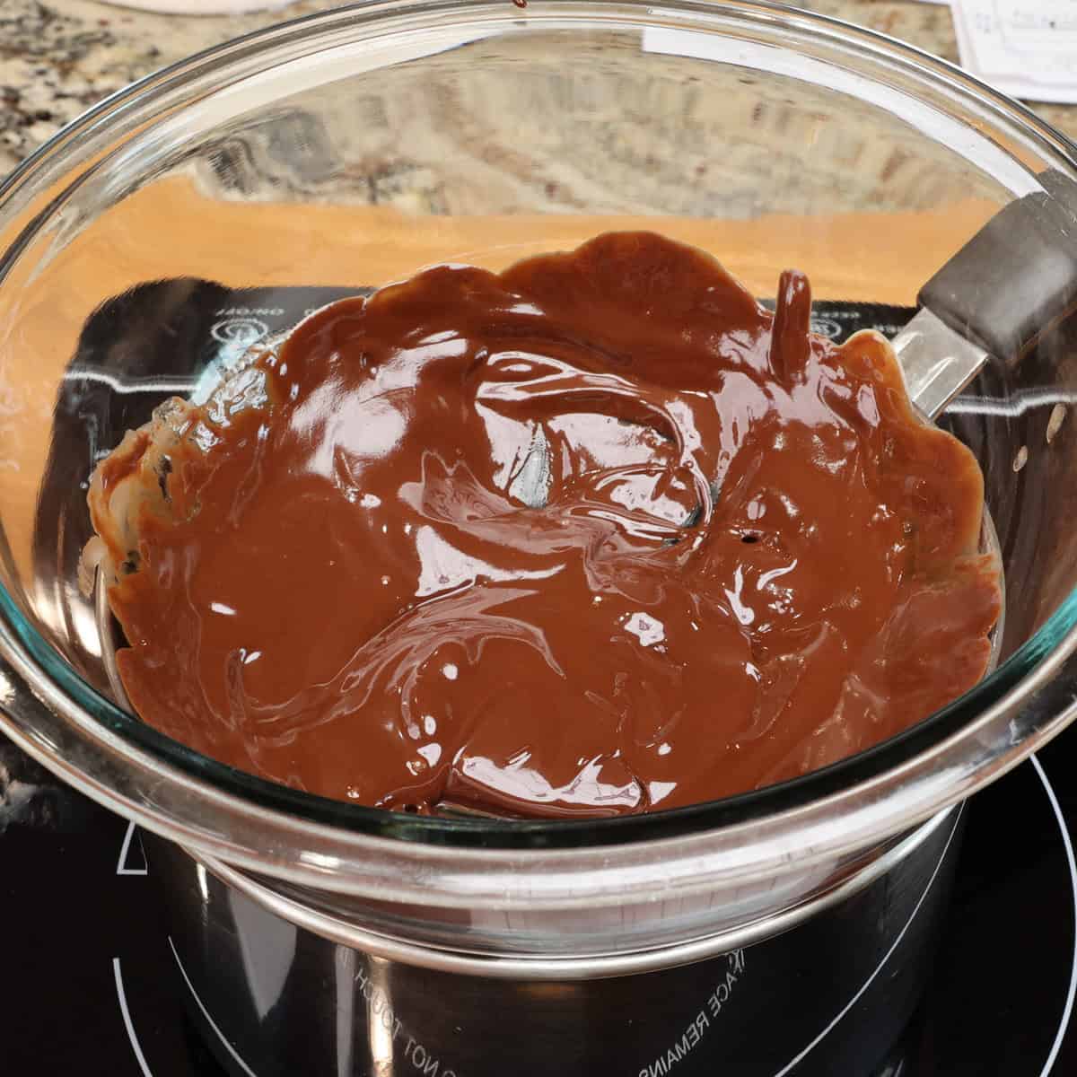 chocolate ganache in a mixing bowl set over a pot of simmering water.