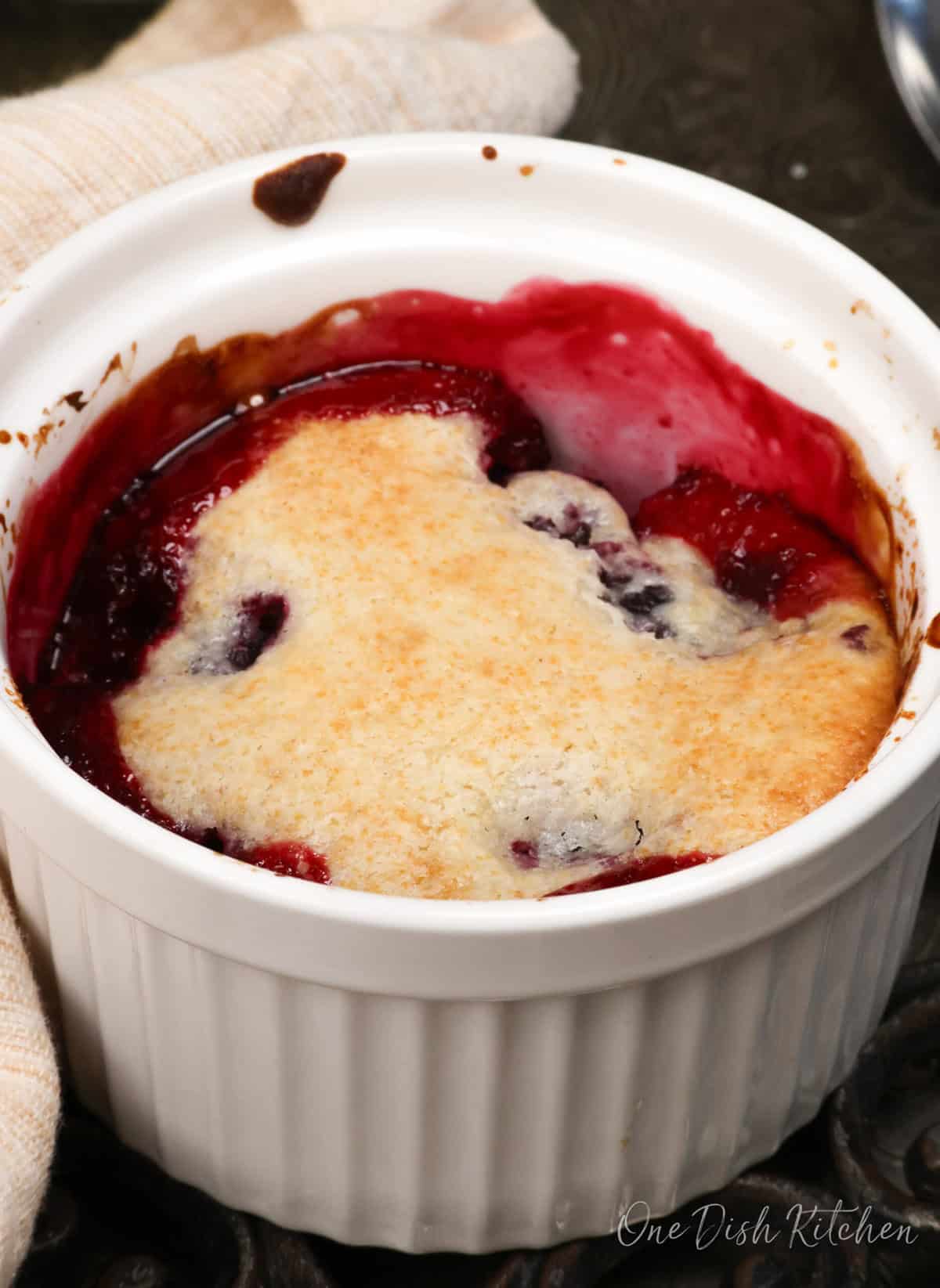 a single serving blackberry cobbler in a white ramekin.