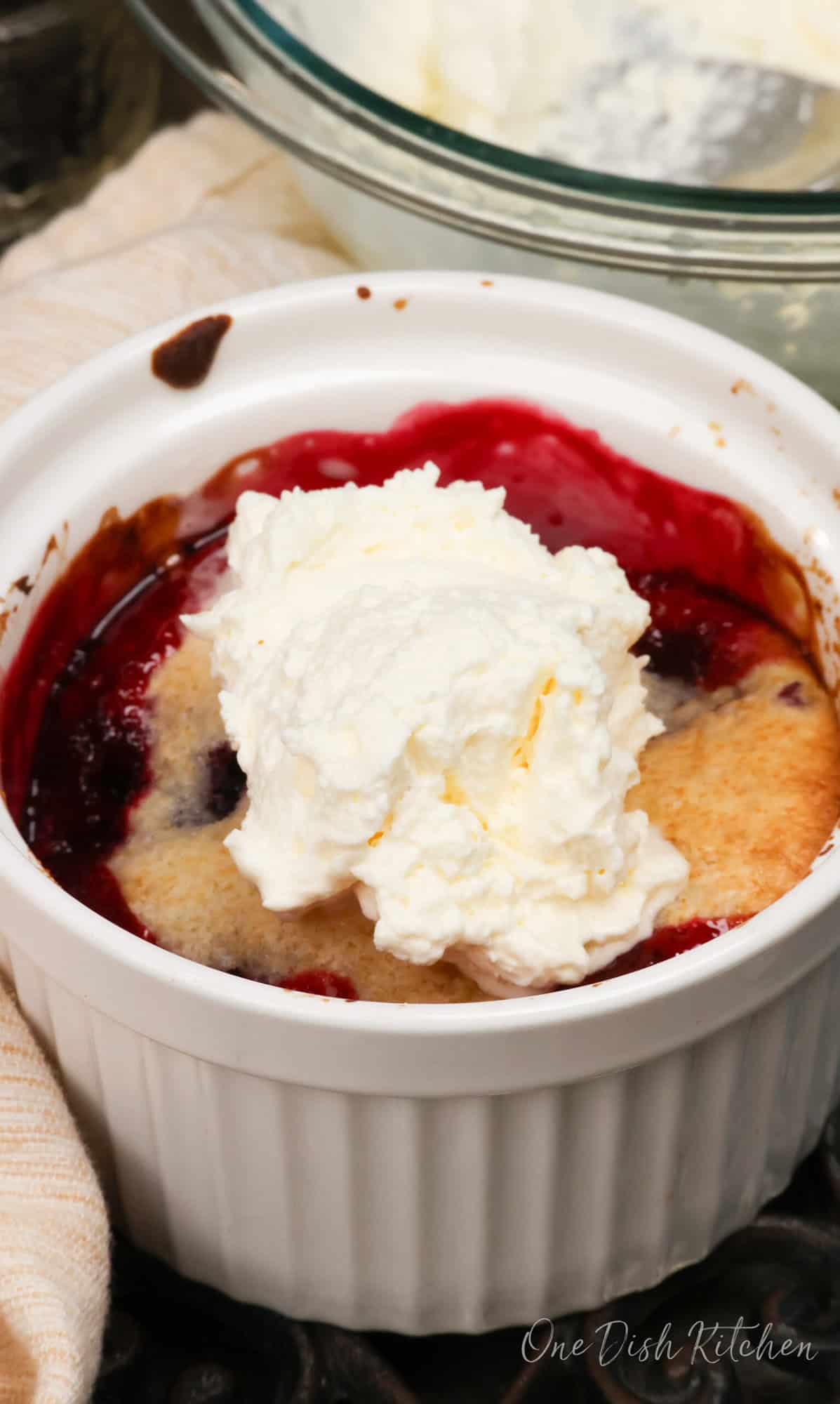 an individual blackberry cobbler topped with whipped cream.