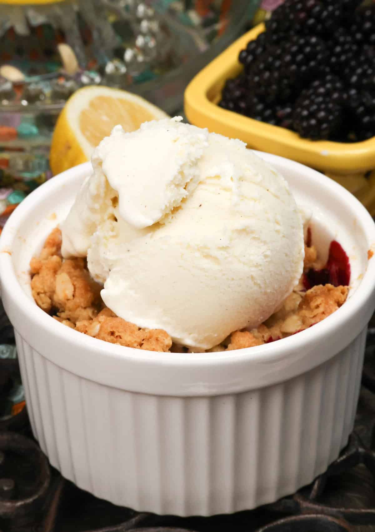 a mini blackberry crisp topped with a scoop of vanilla ice cream.