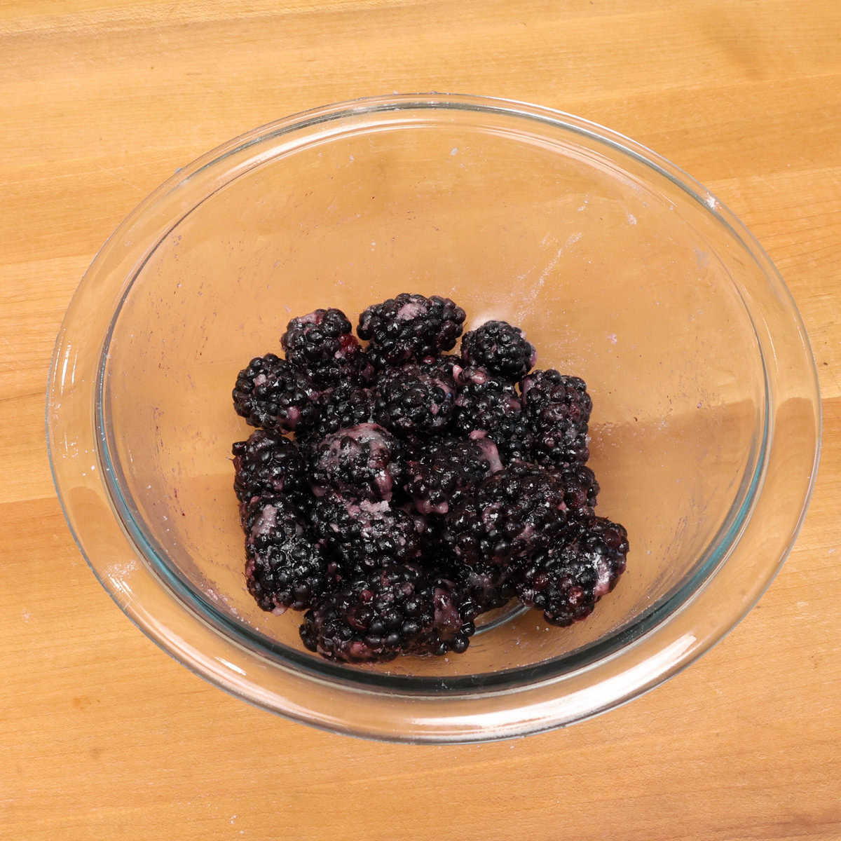 blackberries and sugar in a clear bowl.