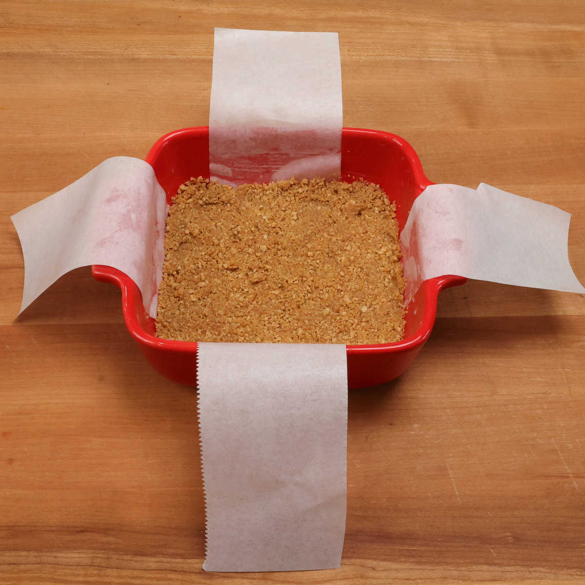 graham cracker crumbs in a small red baking dish.