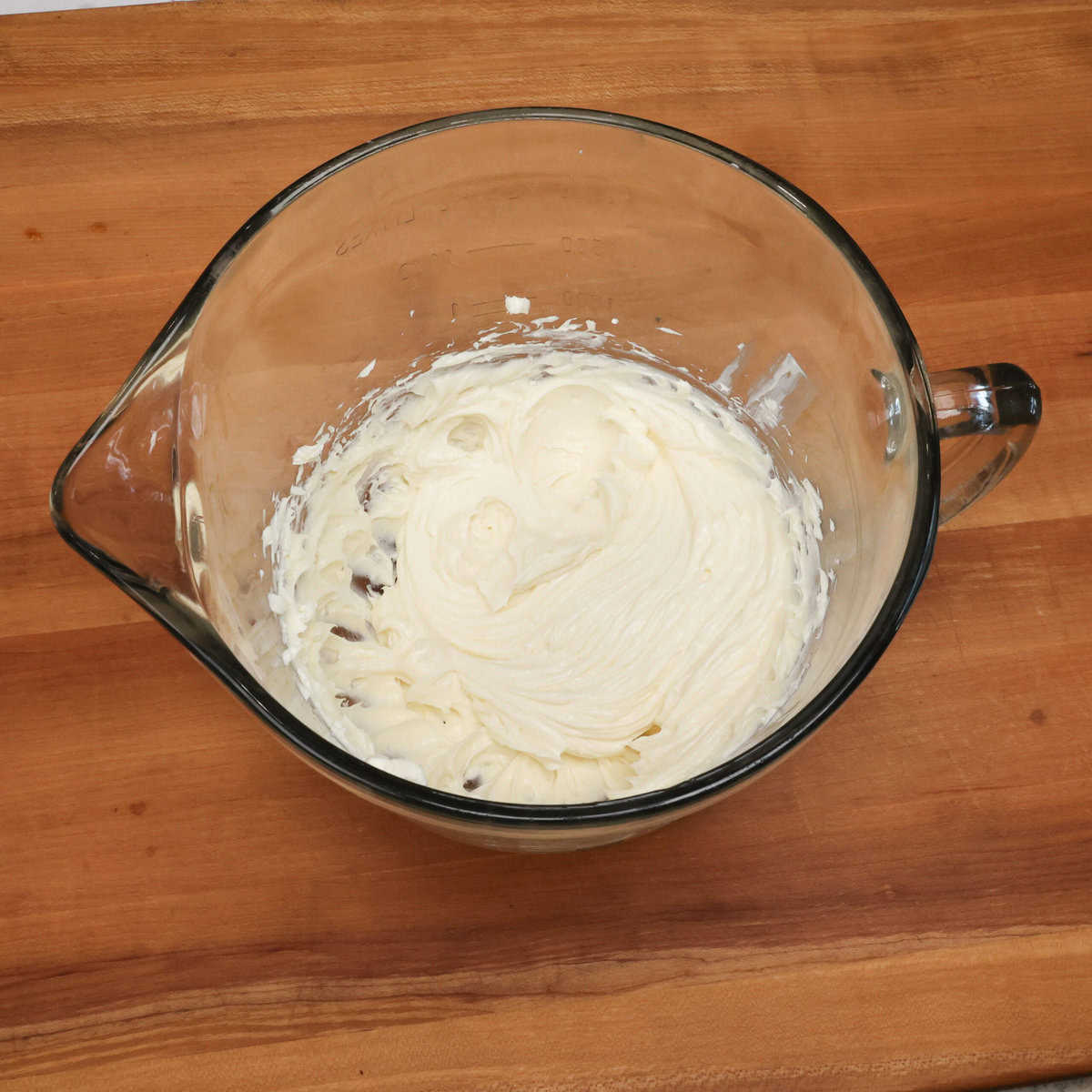 cream cheese in a mixing bowl with sugar, sour cream and vanilla.