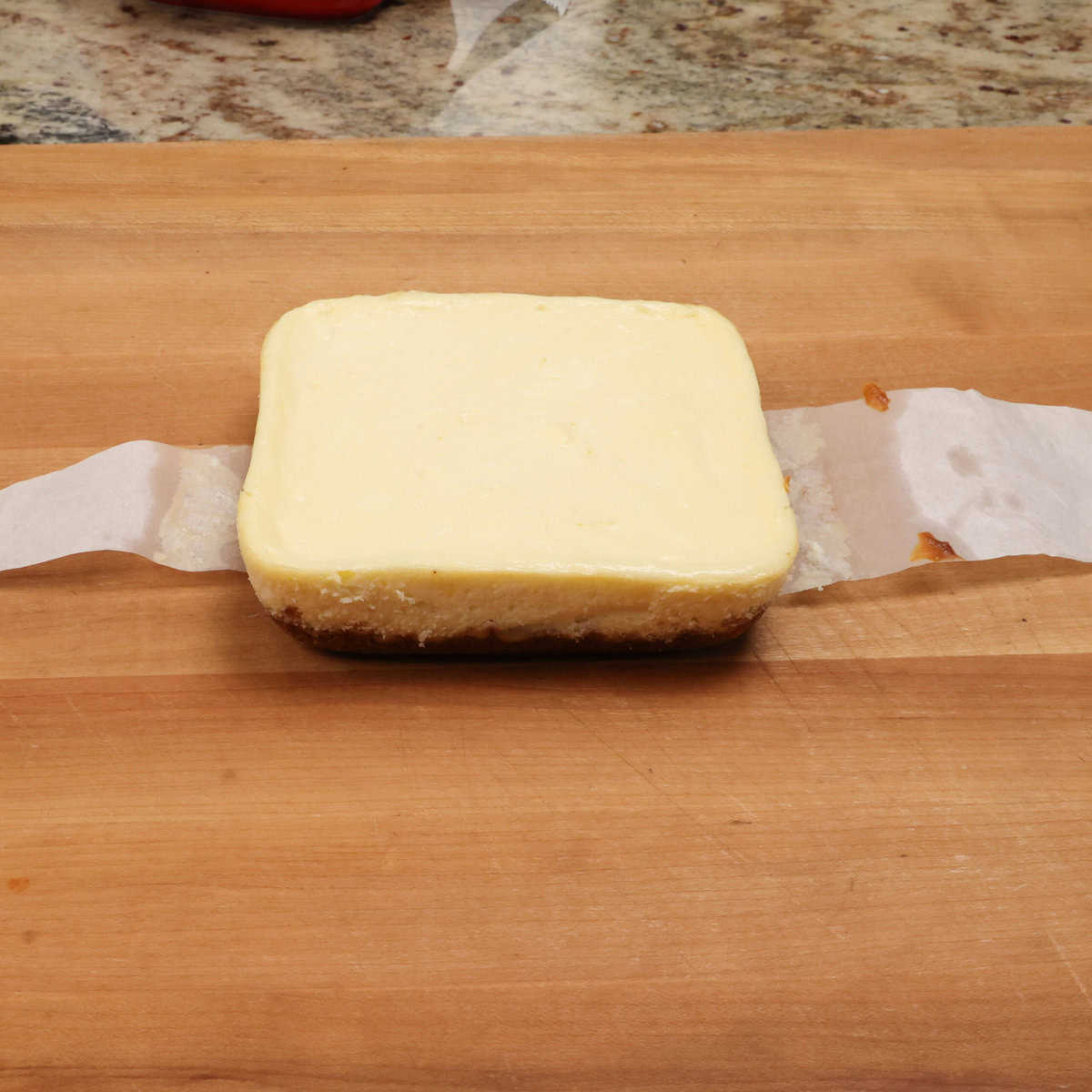 a cheesecake lifted out of the baking dish and on a cutting board.