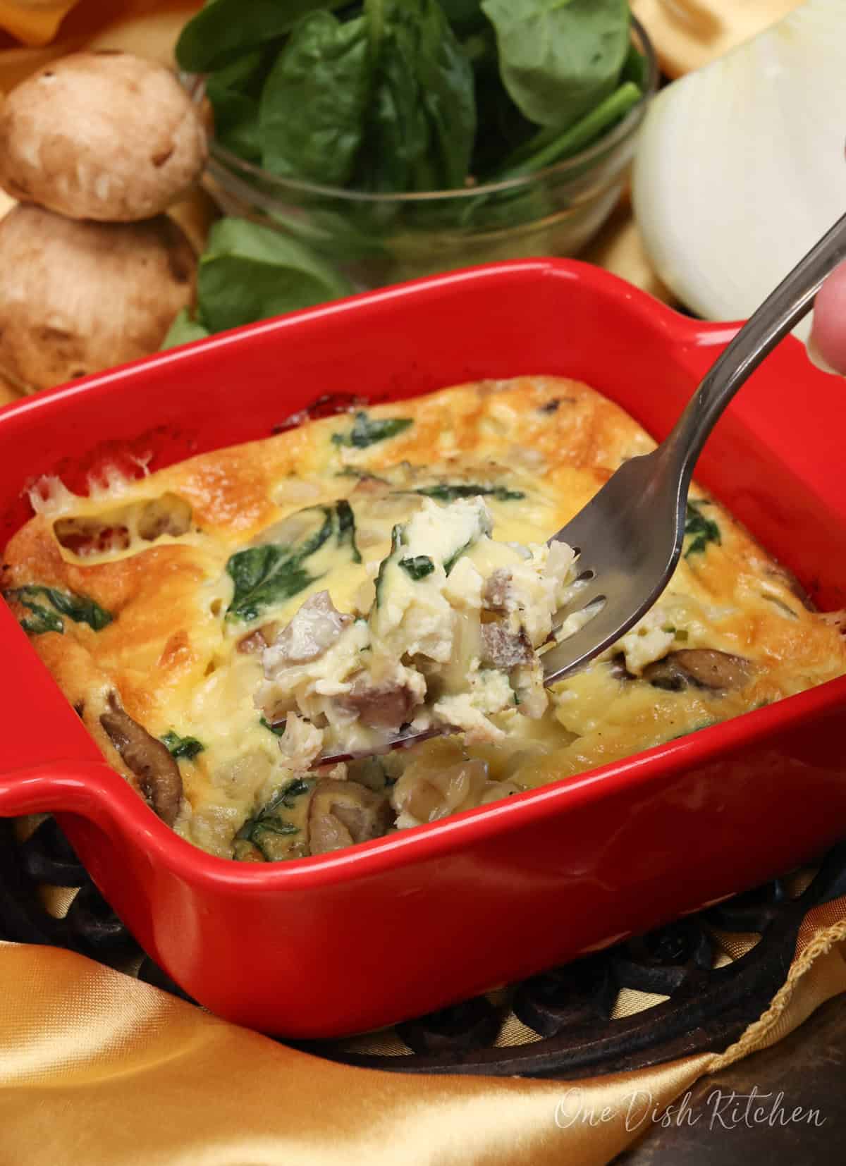 a spinach mushroom quiche with a fork on the side of the dish.