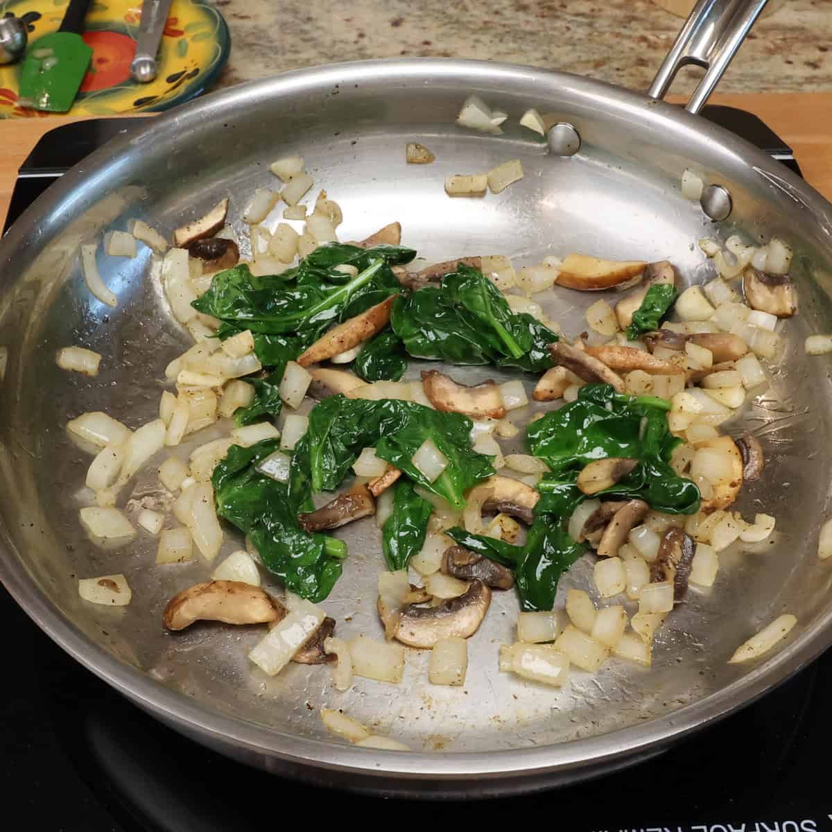 spinach, mushrooms and onions in a skillet.