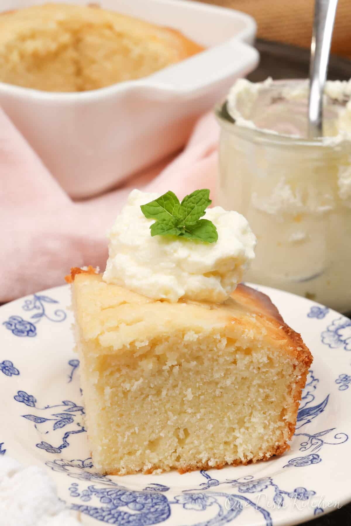 a slice of lemon cake topped with whipped cream next to a pink napkin.