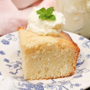 a slice of lemon cake topped with whipped cream next to a pink napkin.