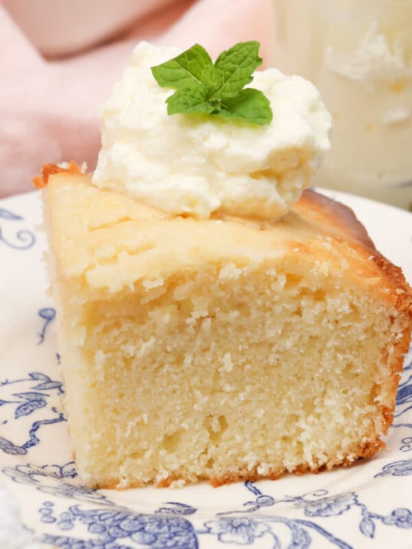 a slice of lemon cake topped with whipped cream next to a pink napkin.