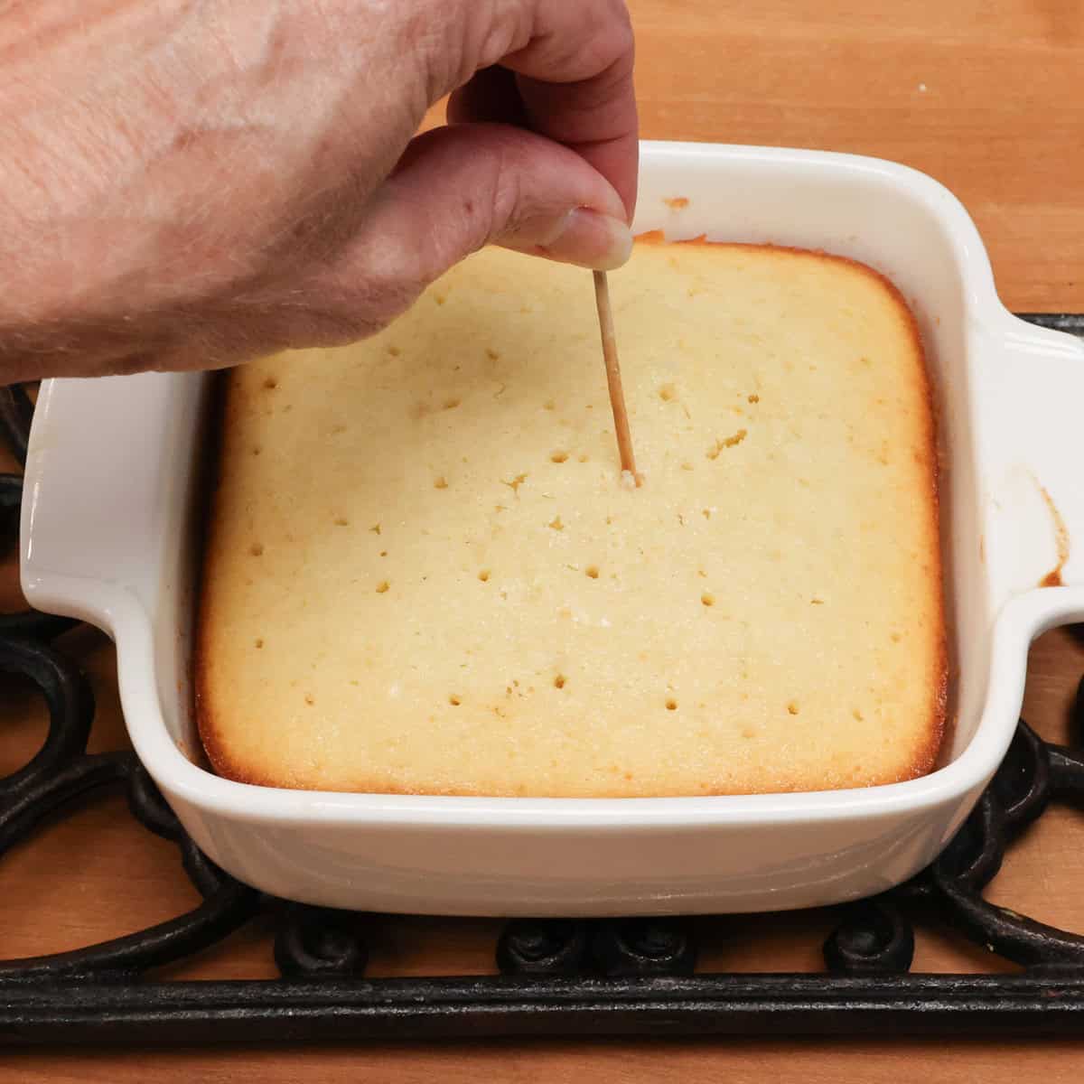 poking holes in a lemon cake with a toothpick.