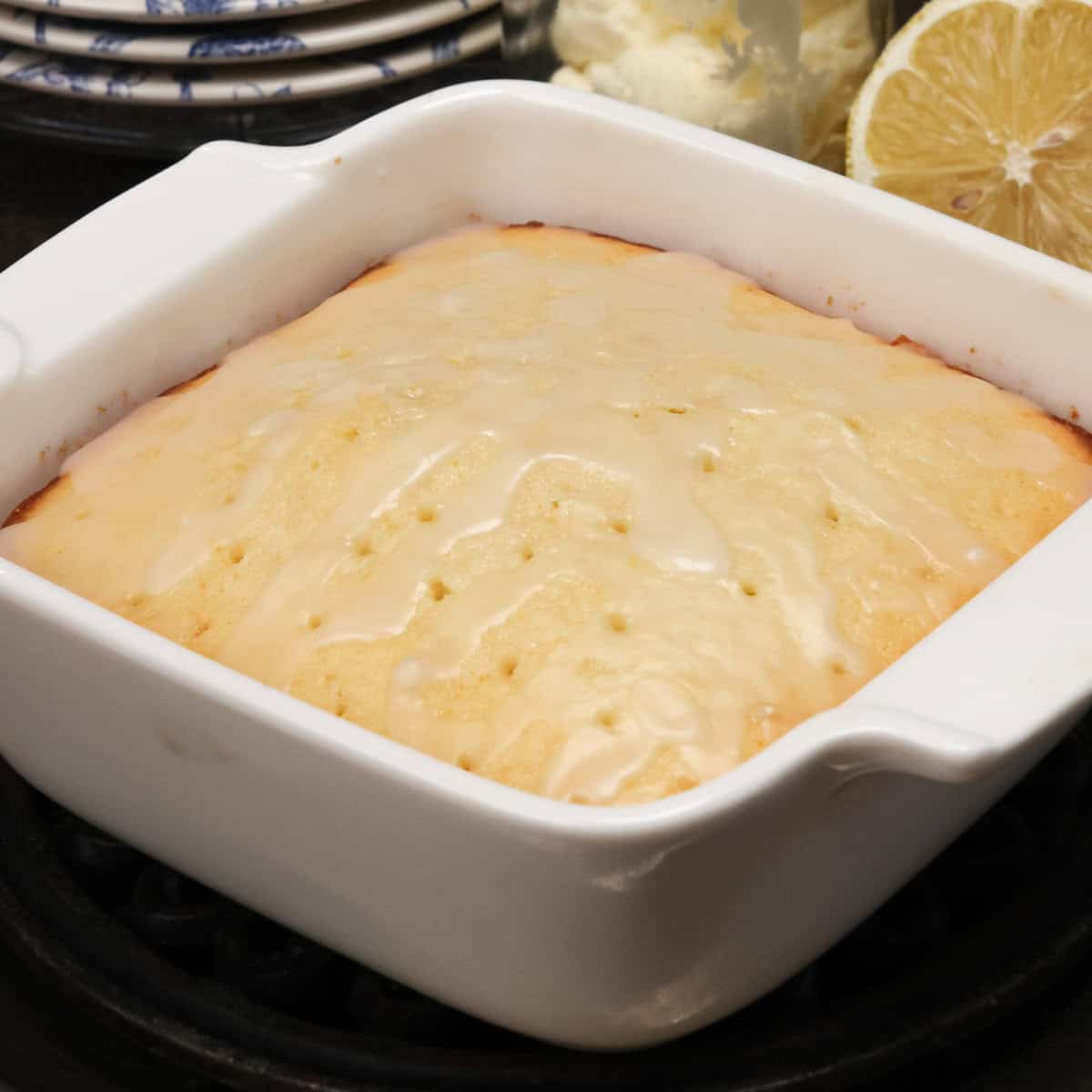 a small lemon cake on a silver tray next to fresh lemons.