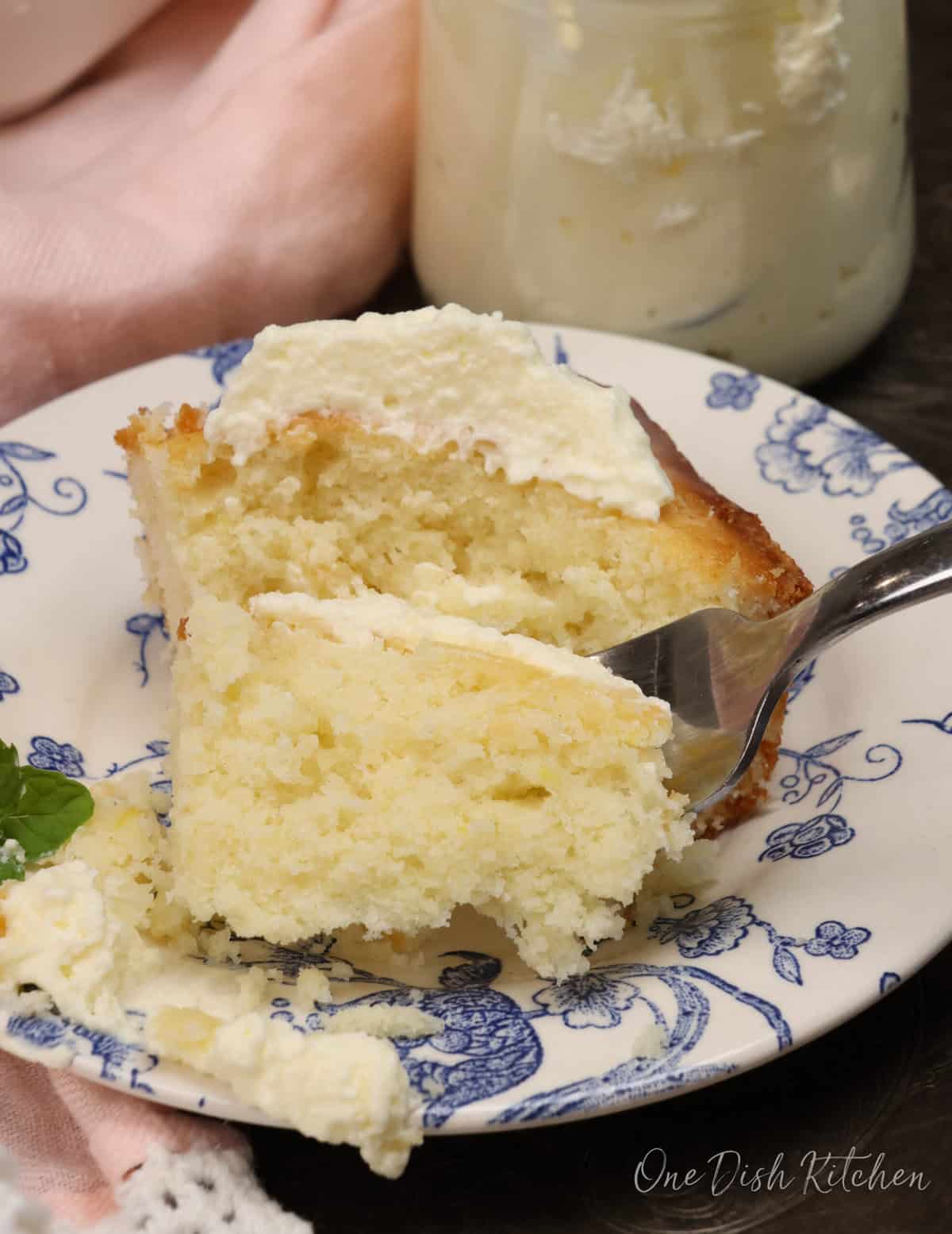 a slice of lemon cake on a blue and white plate with a fork on the side.