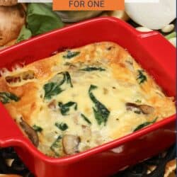 a crustless quiche with spinach and mushrooms in a red square baking dish.