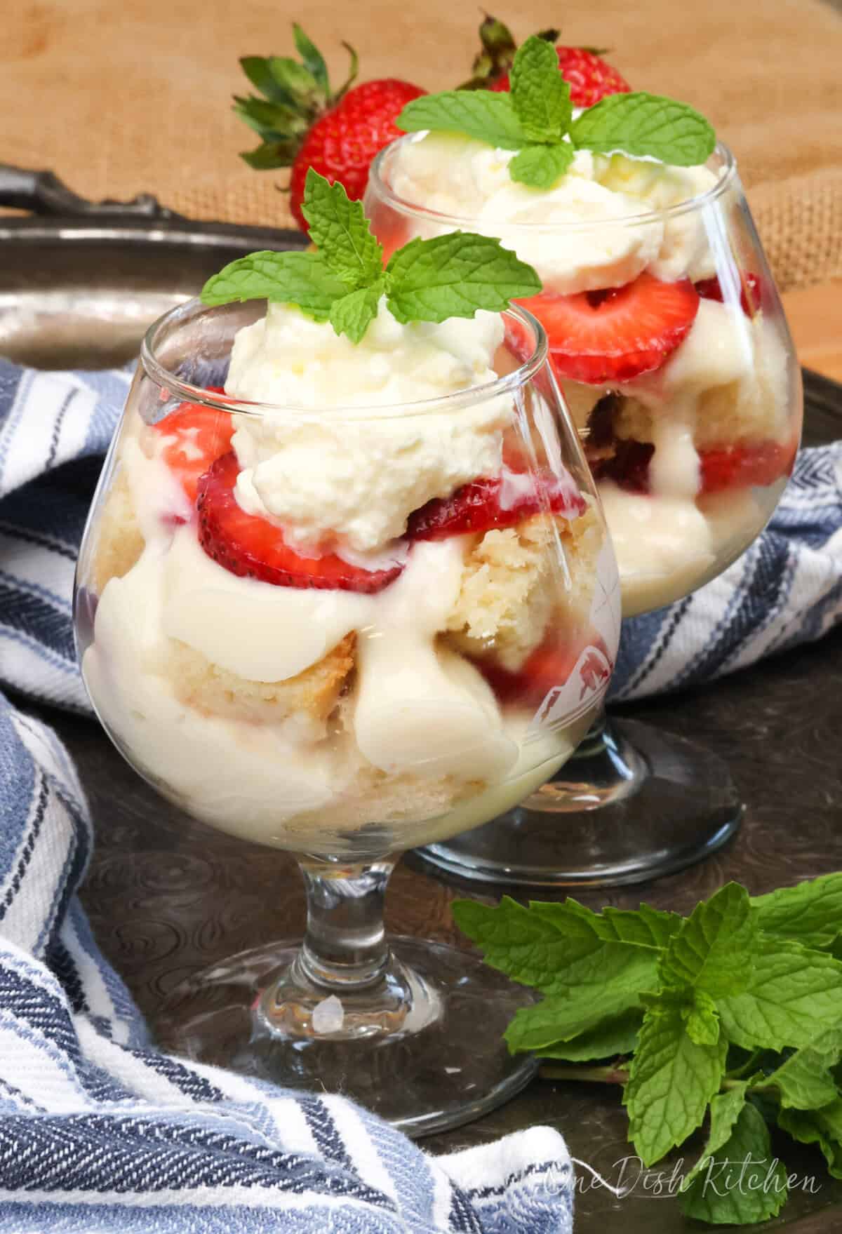 two individual trifles on a silver tray next to a blue napkin.