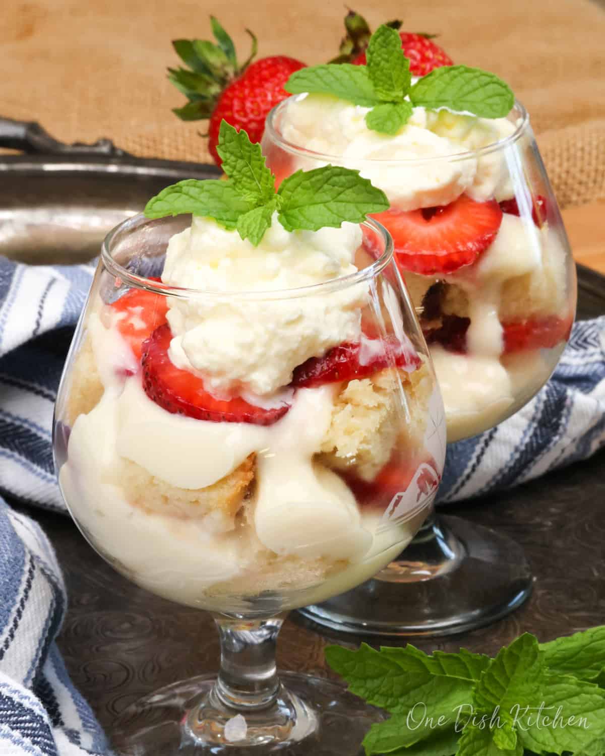 two individual trifles on a silver tray next to a blue napkin.