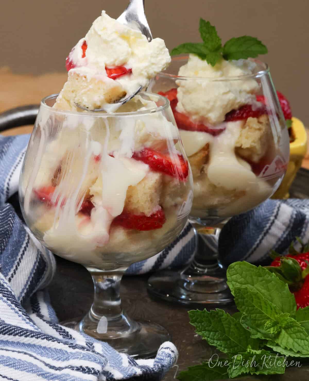 two mini trifles on a tray with a spoon inside the dish.