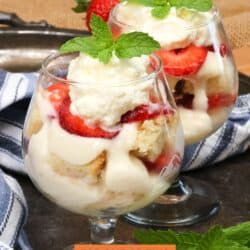 two individual trifles on a silver tray next to a blue napkin.